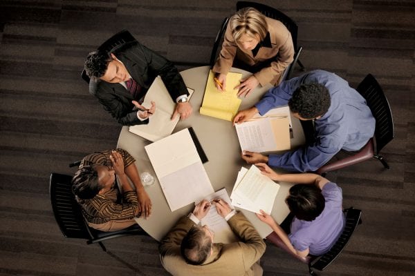 People seating around a table with notepads.