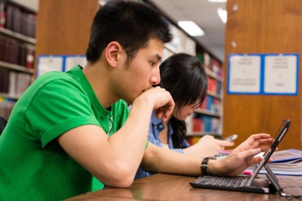 Small image of a two students and one is working at a computer.